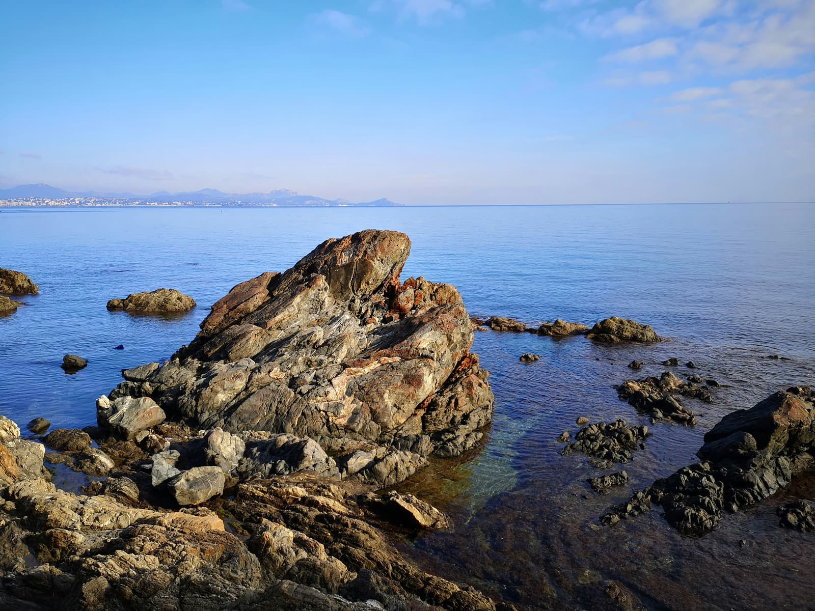 Rocks and clear water on the Saint-Aygulf shore, the Estérel on the horizon