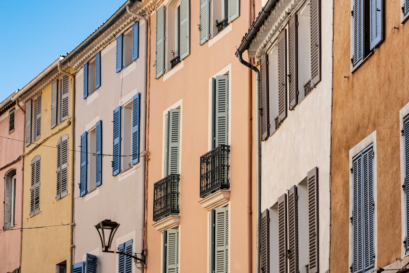 Pink and yellow façades with blue and green shutters in the old town of Fréjus